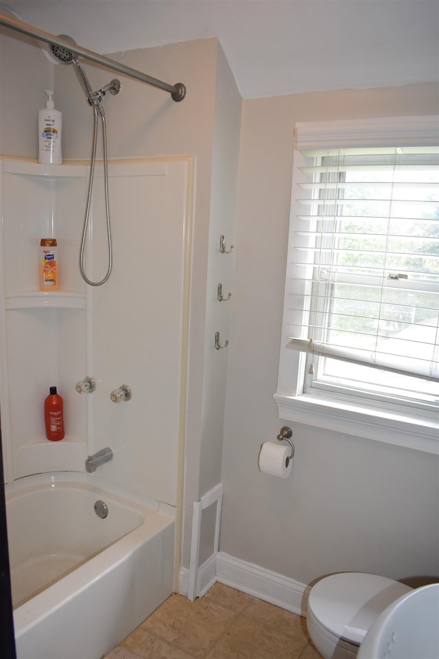 bathroom featuring toilet, bathing tub / shower combination, baseboards, and tile patterned floors