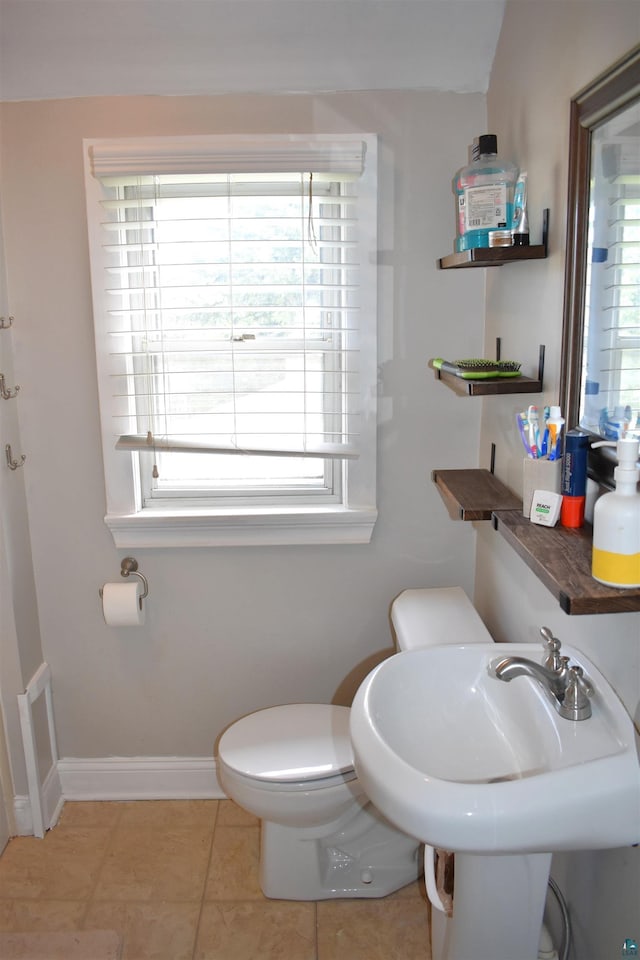 bathroom with toilet, baseboards, tile patterned floors, and a sink