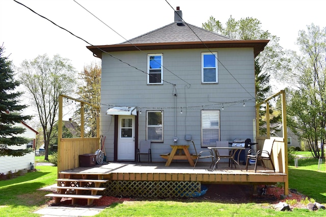 rear view of house featuring a lawn, roof with shingles, and a wooden deck