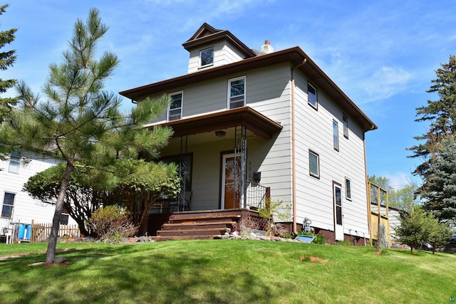 american foursquare style home with a porch, a front lawn, and a chimney