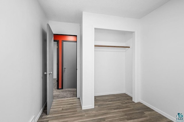733 13th Ave, Two Harbors, MN 55616 - unfurnished bedroom with wood finished floors, a closet, a textured ceiling, and baseboards