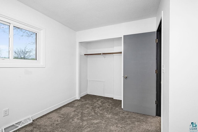 733 13th Ave, Two Harbors, MN 55616 - unfurnished bedroom with dark carpet, a closet, and a textured ceiling