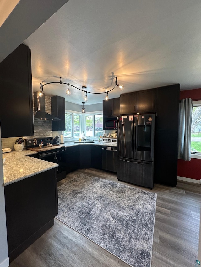 706 28th St, Cloquet, MN 55720 - kitchen with black appliances, wall chimney range hood, a sink, tasteful backsplash, and wood finished floors