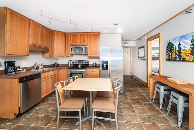 21 E Wisconsin St Unit 301, Grand Marais, MN 55616 - kitchen featuring stainless steel appliances, a sink, stone finish flooring, dark countertops, and brown cabinets