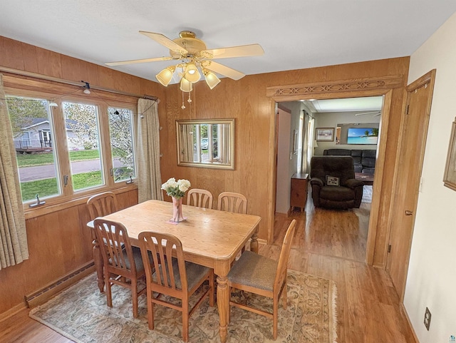 602 26th St, Cloquet, MN 55720 - dining area with light wood-style floors, ceiling fan, wood walls, and a baseboard heating unit