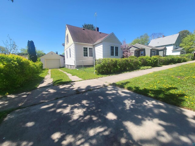 111 E Nebraska Ave, Gilbert, MN 55741 - view of side of home featuring a detached garage, an outbuilding, driveway, a chimney, and a yard