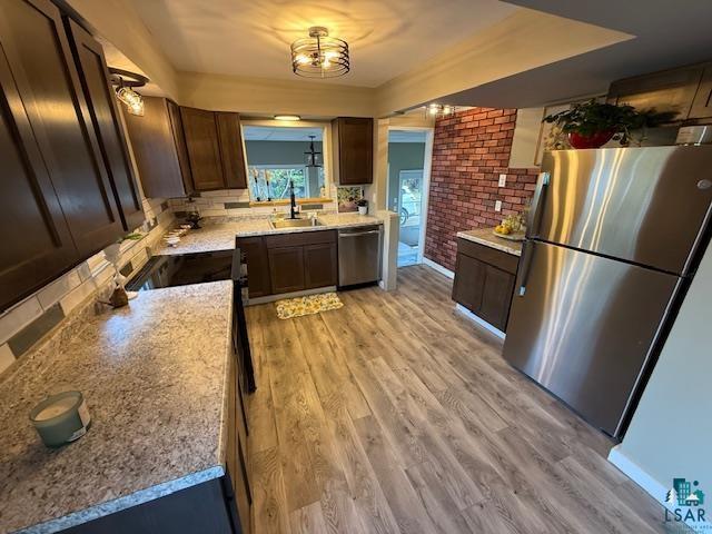 710 N Boundary Ave, Duluth, MN 55810 - kitchen featuring stainless steel appliances, a sink, brick wall, light wood finished floors, and light countertops