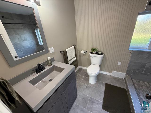 710 N Boundary Ave, Duluth, MN 55810 - full bathroom featuring toilet, vanity, baseboards, tiled shower, and tile patterned flooring
