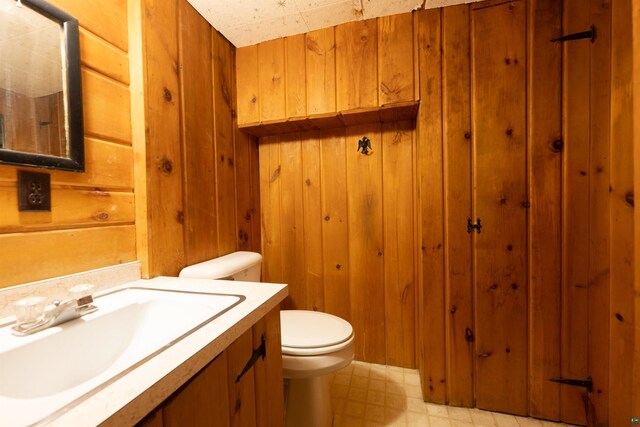 1205 Summit Ave, Cloquet, MN 55720 - half bath featuring wooden walls, toilet, tile patterned floors, and vanity
