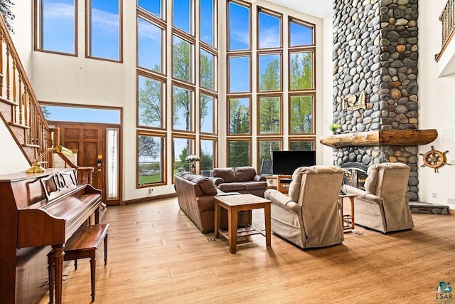 5491 N Shore Dr, Duluth, MN 55804 - living room with a towering ceiling, stairway, light wood-style floors, baseboards, and a stone fireplace