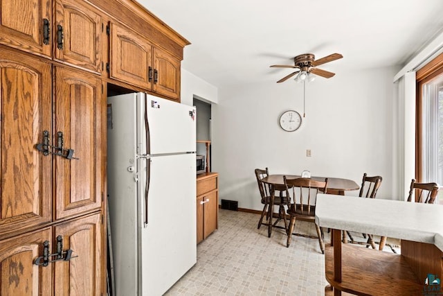 2611 Chambersburg Ave, Duluth, MN 55811 - kitchen featuring freestanding refrigerator, ceiling fan, brown cabinets, stainless steel microwave, and baseboards