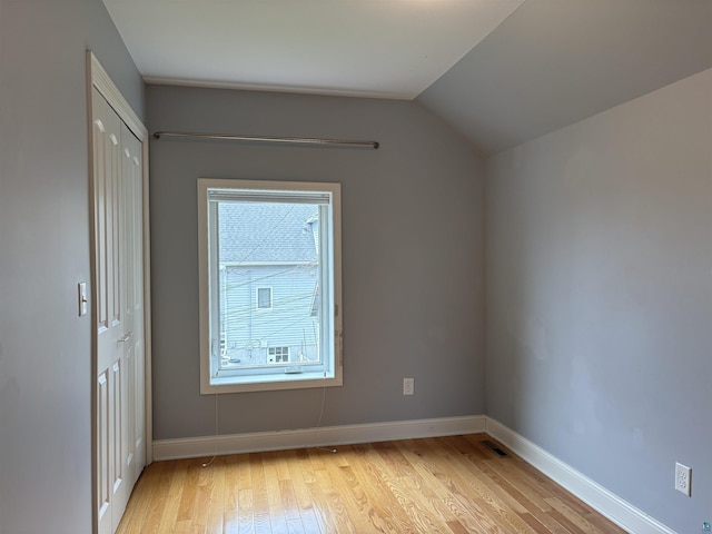 819 N 10th Ave E, Duluth, MN 55805 - unfurnished bedroom with light wood-style floors, vaulted ceiling, baseboards, and a closet