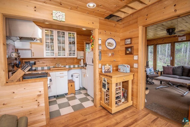 258 Soderberg Ln, Grand Marais, MN 55604 - kitchen with wall chimney exhaust hood, white cabinetry, wood walls, glass insert cabinets, and wooden ceiling