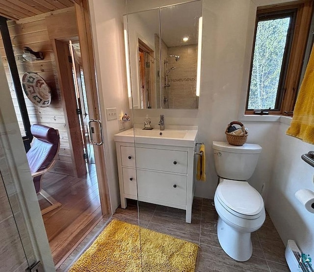 258 Soderberg Ln, Grand Marais, MN 55604 - bathroom with vanity, toilet, a stall shower, baseboard heating, and wood finished floors