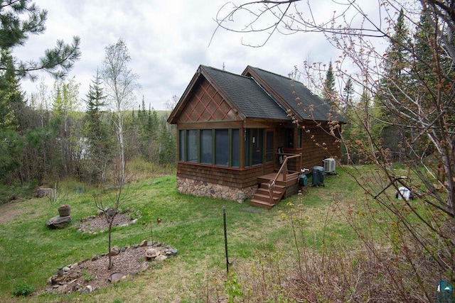 258 Soderberg Ln, Grand Marais, MN 55604 - back of house featuring a sunroom, a shingled roof, and a lawn