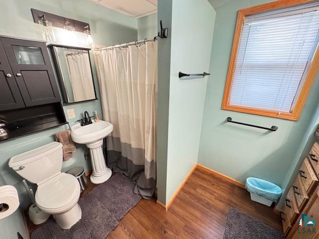 1917 Greysolon Rd, Duluth, MN 55812 - bathroom with wood finished floors, toilet, curtained shower, and baseboards