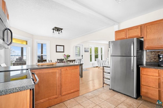 619 W Skyline Pkwy, Duluth, MN 55806 - kitchen with stainless steel appliances, arched walkways, light tile patterned floors, dark countertops, and tasteful backsplash