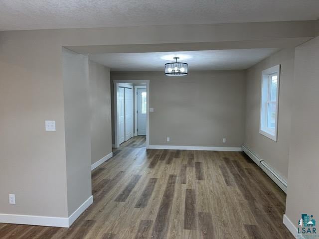 402 N Elba Ave, Eveleth, MN 55734 - spare room featuring a baseboard radiator, wood finished floors, baseboards, and a chandelier