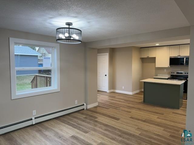 402 N Elba Ave, Eveleth, MN 55734 - kitchen featuring baseboard heating, stainless steel appliances, light wood-type flooring, baseboards, and a textured ceiling