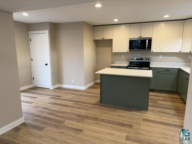 402 N Elba Ave, Eveleth, MN 55734 - kitchen with stainless steel microwave, range with electric cooktop, baseboards, a center island, and light wood finished floors