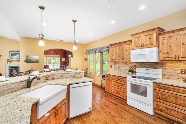 5036 Silver Leaf St, Hermantown, MN 55811 - kitchen with white appliances, decorative backsplash, arched walkways, light wood finished floors, and a lit fireplace