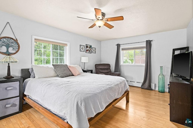 13107 W 9th St, Duluth, MN 55808 - bedroom with a baseboard radiator, light wood-style floors, a ceiling fan, and a textured ceiling