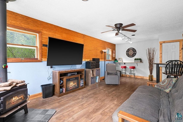 13107 W 9th St, Duluth, MN 55808 - living area with a wood stove, ceiling fan, track lighting, wood finished floors, and a textured ceiling
