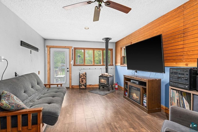 13107 W 9th St, Duluth, MN 55808 - living room featuring a wood stove, a textured ceiling, ceiling fan, wood finished floors, and baseboards