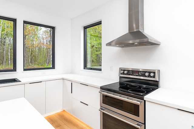 2413 Lismore Rd, Duluth, MN 55804 - kitchen featuring range with two ovens, wall chimney exhaust hood, white cabinets, and light countertops