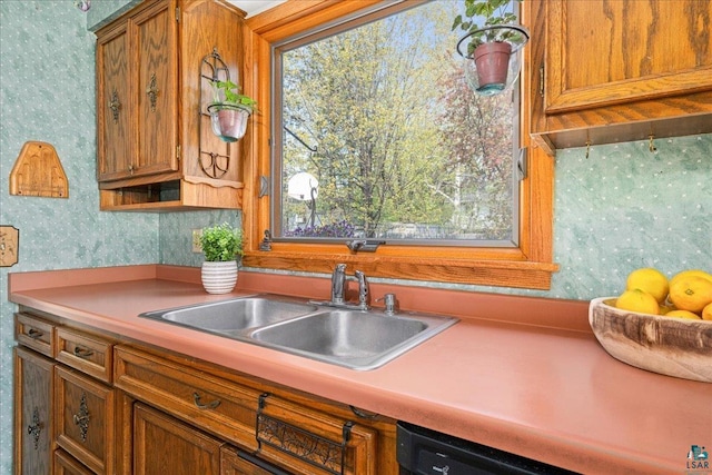 2715 Triggs Ave, Duluth, MN 55811 - kitchen with wallpapered walls, a sink, brown cabinetry, light countertops, and dishwashing machine