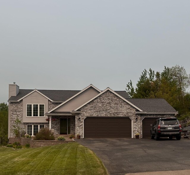 1505 Coachlight Crk, Proctor, MN 55810 - view of front of property with a garage, driveway, a front lawn, a chimney, and brick siding
