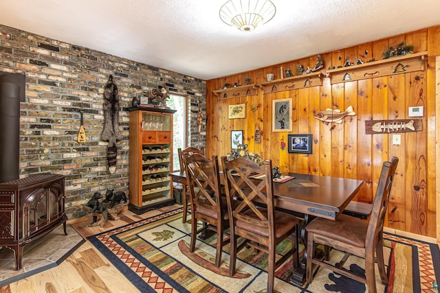 3984 Stocking Point Dr, Ely, MN 55731 - dining room featuring a wood stove, light wood finished floors, wood walls, and a textured ceiling