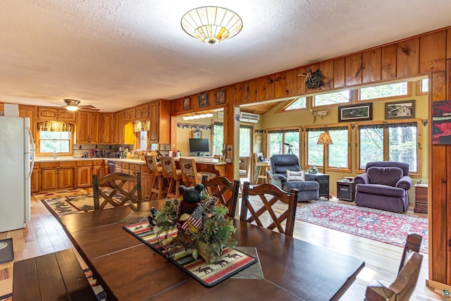 3984 Stocking Point Dr, Ely, MN 55731 - dining space featuring a textured ceiling, light wood-style floors, wood walls, and vaulted ceiling
