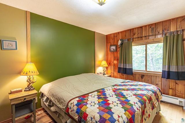 3984 Stocking Point Dr, Ely, MN 55731 - bedroom with baseboard heating, wood walls, and hardwood / wood-style floors