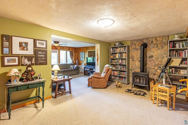 3984 Stocking Point Dr, Ely, MN 55731 - living room featuring a wood stove, a textured ceiling, carpet flooring, and a ceiling fan