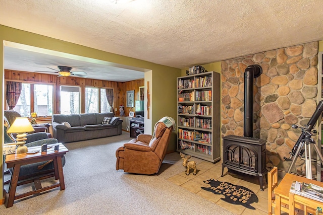 3984 Stocking Point Dr, Ely, MN 55731 - carpeted living area featuring a wood stove, a ceiling fan, a textured ceiling, and wood walls