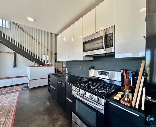 328 Gunflint Trl, Grand Marais, MN 55604 - kitchen with stainless steel appliances, a sink, concrete flooring, and white cabinetry
