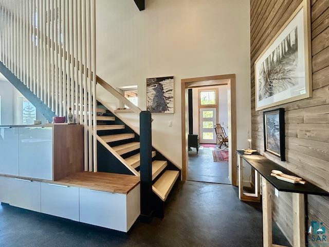 328 Gunflint Trl, Grand Marais, MN 55604 - staircase featuring finished concrete flooring, a high ceiling, and wooden walls