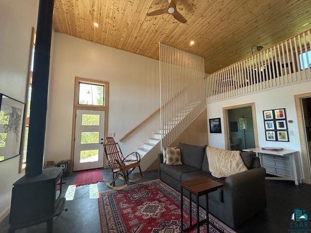 328 Gunflint Trl, Grand Marais, MN 55604 - living room with a wood stove, wood ceiling, a ceiling fan, a towering ceiling, and stairway