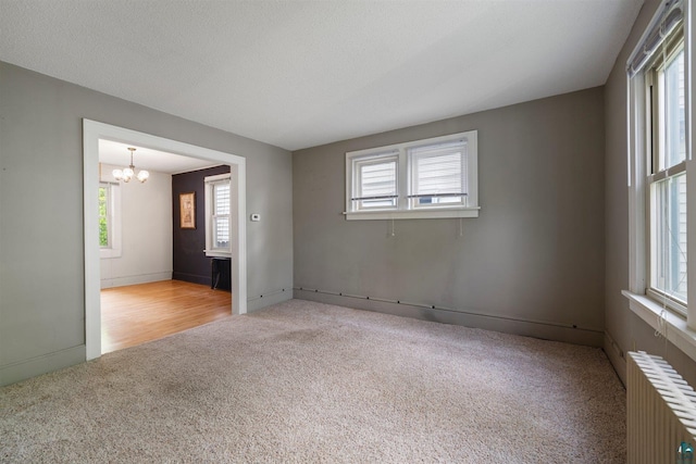 620 Hayes St, Eveleth, MN 55734 - carpeted empty room with radiator, healthy amount of natural light, and a chandelier