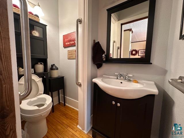 1601 W 4th Ave, International Falls, MN 56649 - half bathroom with wood finished floors, toilet, vanity, and baseboards