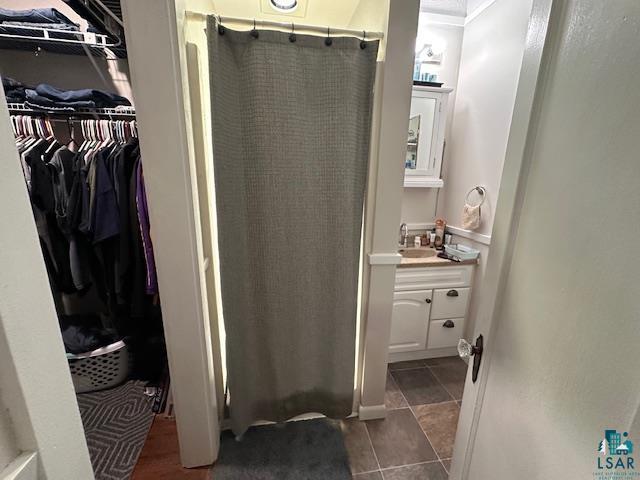 1601 W 4th Ave, International Falls, MN 56649 - bathroom with vanity, a shower stall, a spacious closet, and tile patterned floors