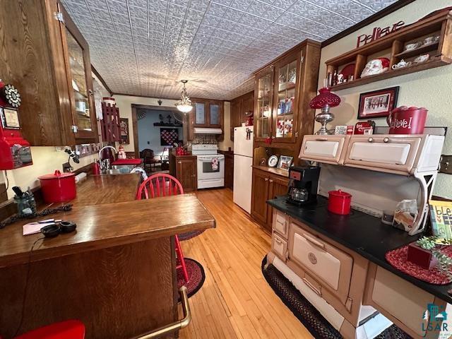 1601 W 4th Ave, International Falls, MN 56649 - kitchen with white appliances, light wood-type flooring, an ornate ceiling, glass insert cabinets, and dark countertops