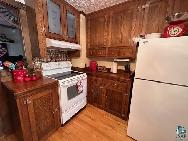 1601 W 4th Ave, International Falls, MN 56649 - kitchen featuring white appliances, under cabinet range hood, dark countertops, light wood-type flooring, and an ornate ceiling