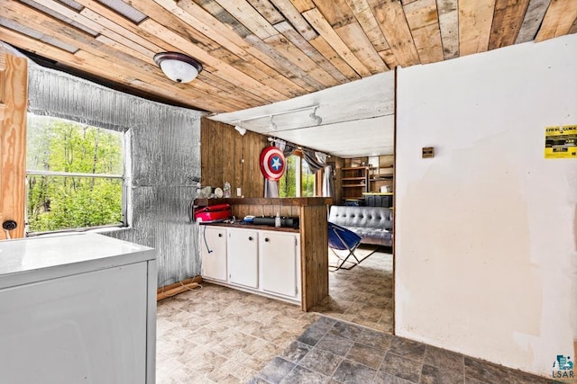 4605 Mccomber Rd, Duluth, MN 55803 - kitchen with white cabinets, wooden ceiling, stone finish flooring, wooden walls, and fridge