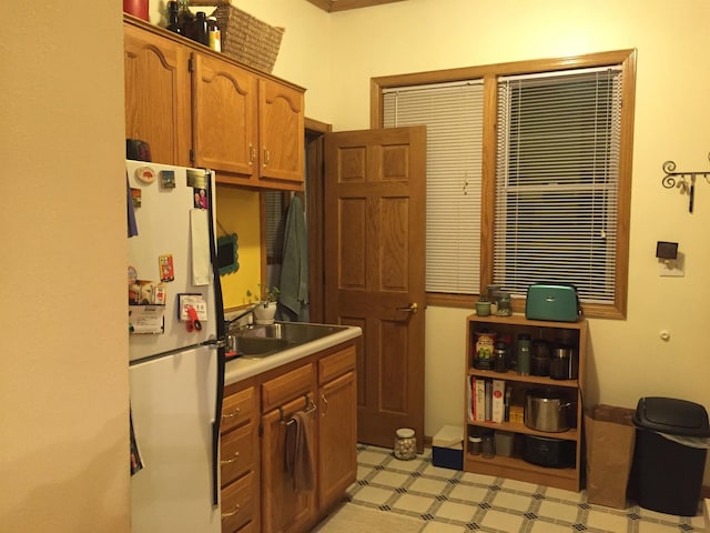 2213 W 10th St, Duluth, MN 55806 - kitchen with freestanding refrigerator, a sink, brown cabinetry, and light countertops