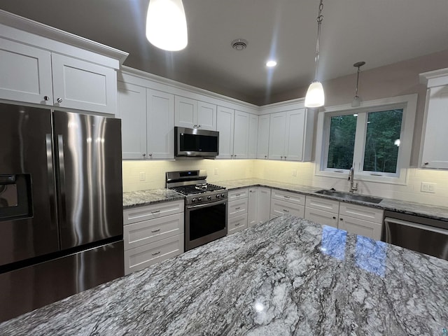 5036 W Arrowhead Rd, Hermantown, MN 55811 - kitchen with stainless steel appliances, tasteful backsplash, white cabinets, stone counters, and hanging light fixtures