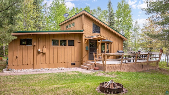 3666 Mackie Rd, Ely, MN 55731 - view of front of home featuring a fire pit, a front yard, board and batten siding, a wooden deck, and crawl space