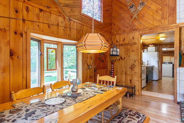 3666 Mackie Rd, Ely, MN 55731 - dining room featuring wooden walls, light wood-type flooring, washer / clothes dryer, and a towering ceiling