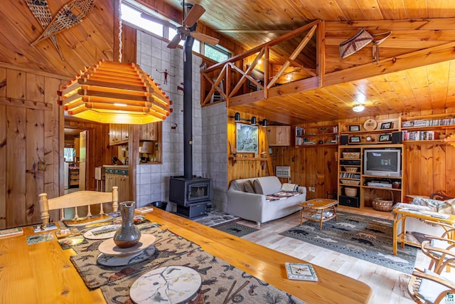 3666 Mackie Rd, Ely, MN 55731 - living room featuring wood walls, a wood stove, wood-type flooring, a ceiling fan, and lofted ceiling